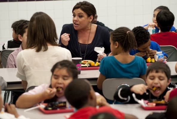 La reconocida chef Rachael Ray come con niños en una escuela pública para promover alimentos saludables.