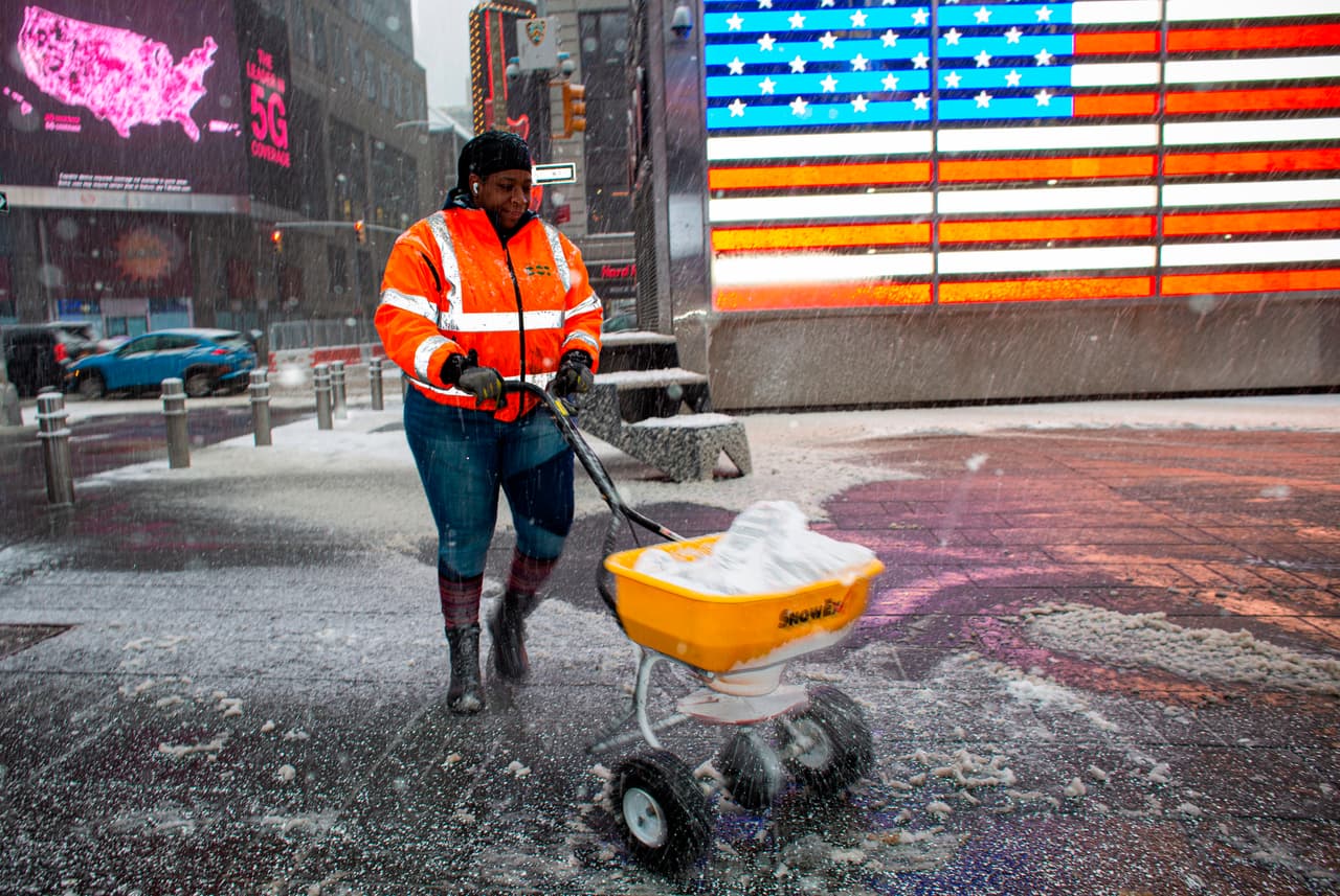 Un trabajador esparce sal mientras cae la nieve en Times Square de Nueva York