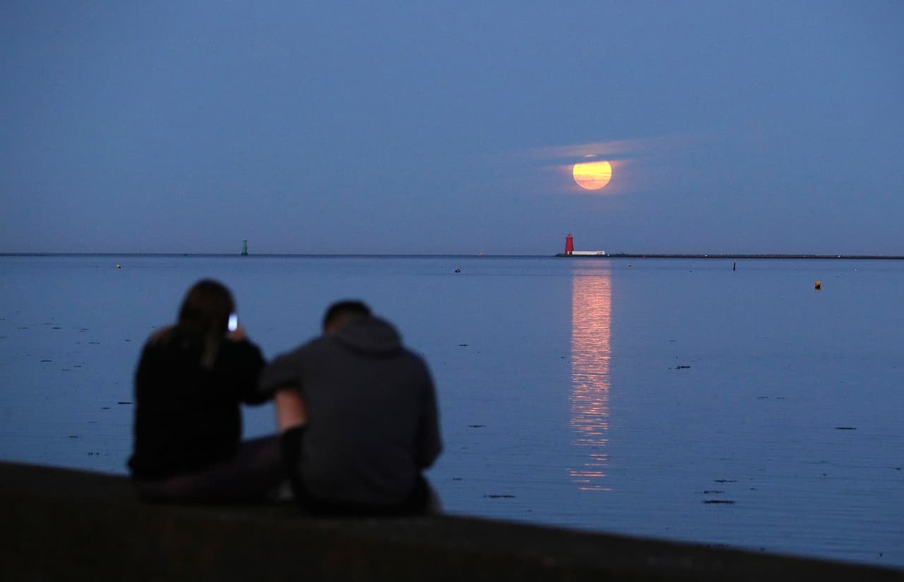 Una pareja contempla la Superluna desde la bahía de Dublín, en Irlanda, este jueves.
<b>La Superluna es un fenómeno que ocurre cuando la luna está en su punto más cercano a la tierra y se ve más grande de lo habitual.</b>