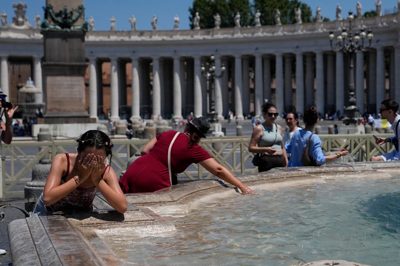 Los fieles católicos que acudieron al rezo del Ángelus junto al papa, en la plaza de San Pedro, se refrescan con el agua de las fuentes.