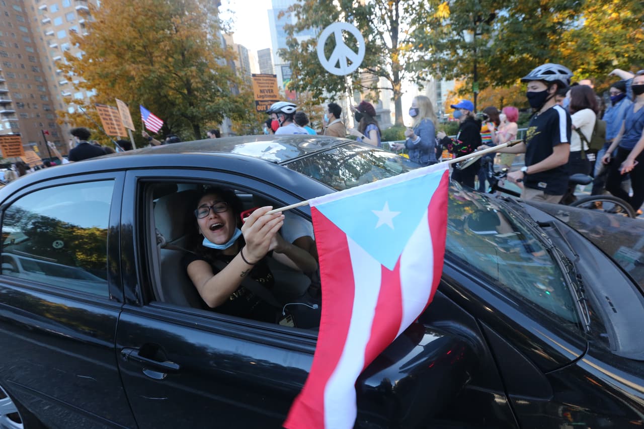 Estos puertorriqueños celebran desde su carro el triunfo de Biden y Harris.