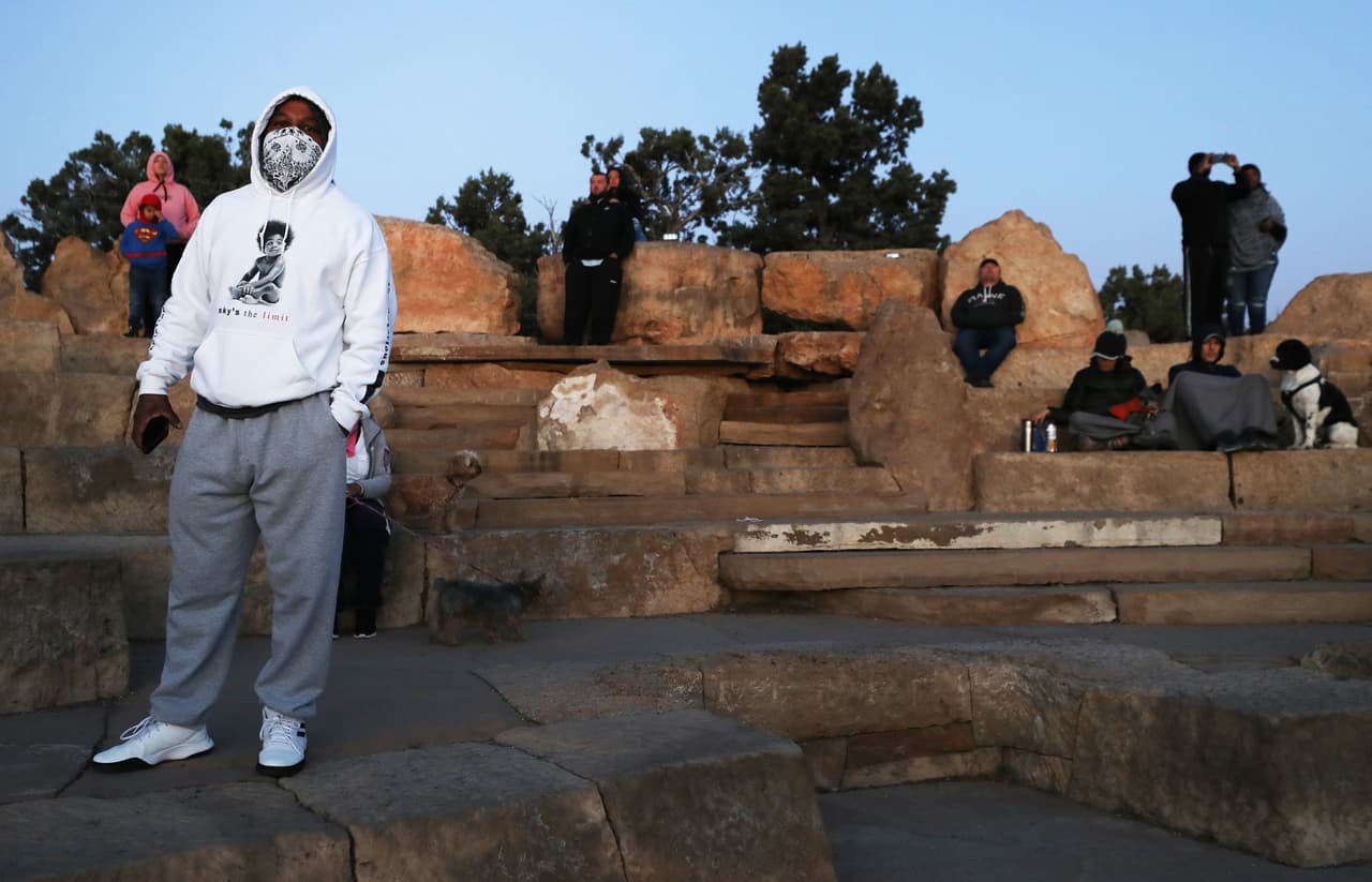 Un hombre se cubre la cara mientras los visitantes se reúnen para ver el amanecer en el Día de los Caídos desde el South Rim del Parque Nacional del Gran Cañón, que se ha reabierto parcialmente los fines de semana en medio de la pandemia de coronavirus.
