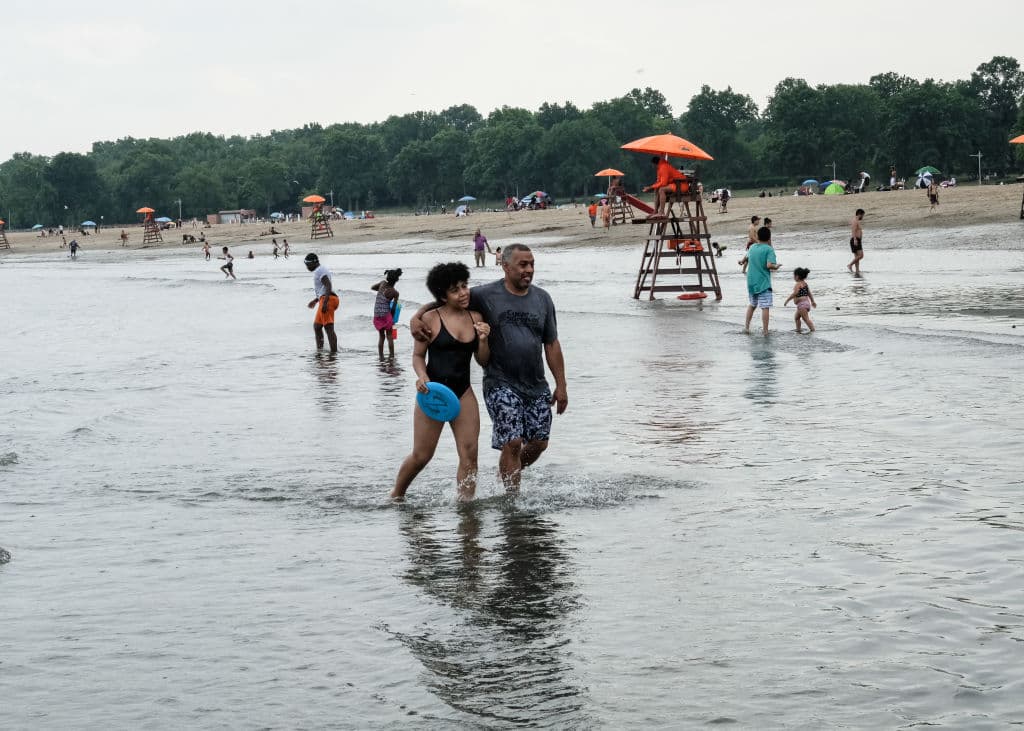 <b><a href="https://www.nycgo.com/venues/orchard-beach">Orchard Beach-Bronx</a></b>
<br>Middletown Road & Stadium Avenue
<br>Tel. (718) 430-1890
<br>
<a href="https://www.google.com/maps/dir/Orchard+Beach,+The+Bronx,+NY/@40.867402,-73.8623333,12z/data=!4m9!4m8!1m0!1m5!1m1!1s0x89c28c5fdfb5d393:0xeb511a8331f79e2f!2m2!1d-73.7922928!2d40.8672934!3e0">Cómo llegar</a>
<br>Esta playa de 1.1 millas, fue llamada “La Rivera de Nueva York” y fue creada en la década de 1930. Entre las razones por las que se le considera una de las mejores de la ciudad, está el sin fin de actividades que puedes encontrar en la zona de 115 acres que la rodean.
<br>
<br>La playa tiene un paseo de bloques hexagonales, áreas para pícnic, dos parques de juegos para niños y
<b> 26 canchas para deportes como baloncesto y voleibol. </b>
<br>