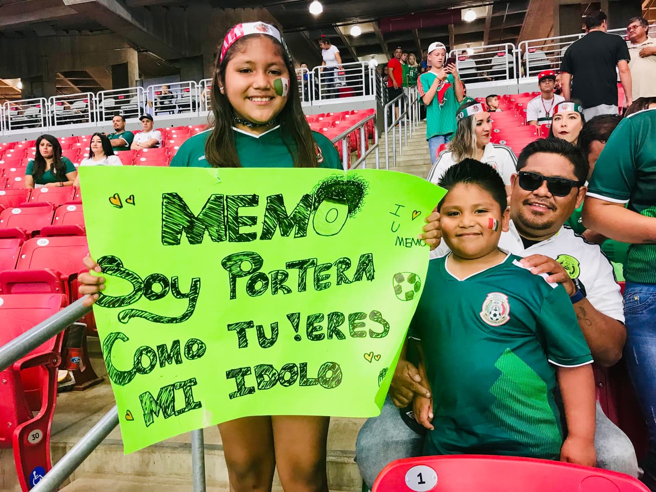 “Memo soy portera como tú” puso esta niña en un letrero con esperanza que el jugador Ochoa lo vea.
<br>
