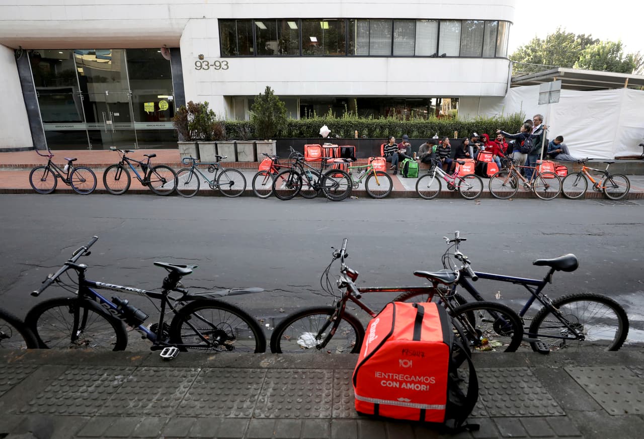 Los ciclistas de
<i>Rappi</i>
<b>carecen de beneficios que son obligatorios para los empleados con salario mínimo, seguro médico o licencia por enfermedad. </b>También deben pagar el mantenimiento de sus bicicletas y comprar una mochila naranja. Muchos se quejan de que los pagos están cayendo a medida que más trabajadores independientes se unen a la plataforma y compiten por cada entrega. Según Rappi, el sistema no retiene nada del dinero de la transacción sino que cobra a los vendedores asociados a la aplicación una tarifa.