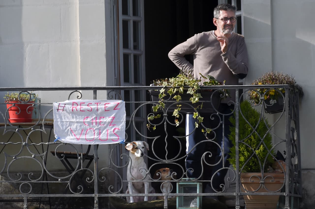 Un hombre en su balcón con una pancarta que dice "quédese en casa", en Nantes. El 17 de marzo entró en vigor una estricta cuarentena para detener la propagación del covid-19 en el país. Mucha gente intenta superar el aislamiento social impuesto por el cierre debido al coronavirus.
<br>
