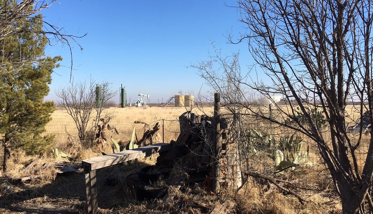 La vista de la casa de la familia Polinske en las afueras de Midland, Texas. Campos de algodon con arbustos de mezquite y pozos de petroleo.