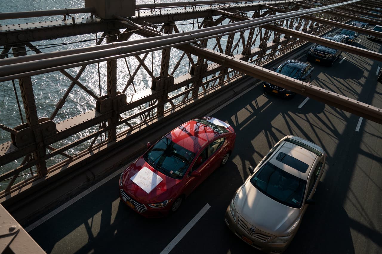 "Trabajadores, no esclavos" se lee en otro cartel que lleva un auto de Uber por el puente de Brooklyn, en Nueva York.
<br>