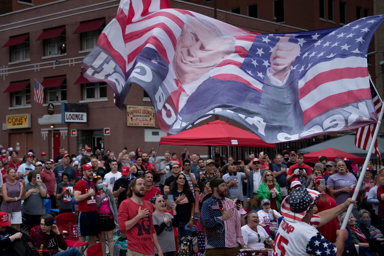Decenas de simpatizantes del mandatario se reunieron desde temprano en las afueras de la entrada del BOK Center de Tulsa, Oklahoma. En la imagen ondean una bandera de EEUU con el rostro del presidente. En la foto también se observa que algunos de los partidarios no llevan mascarillas, en medio de la preocupación por los contagios que pueden darse en ese tipo de aglomeraciones de personas.