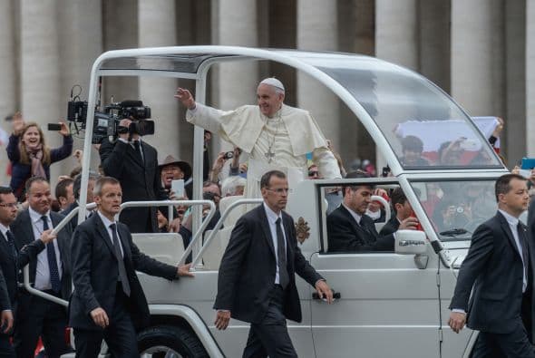 El papa Francisco es custodiado por los miembros de su equipo de seguridad mientras saluda a la multitud.