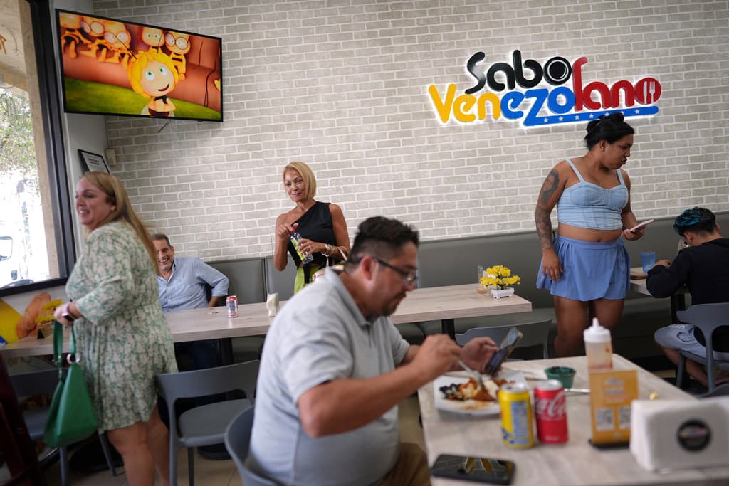 Clientes comen dentro de uno de los restaurantes de Sabor Venezolano, propiedad de Wilmer Escaray, que gestiona una docena de negocios que contratan a migrantes venezolanos como fue él en su día, en Doral, Florida, el martes 1 de abril de 2025. (AP Foto/Rebecca Blackwell)