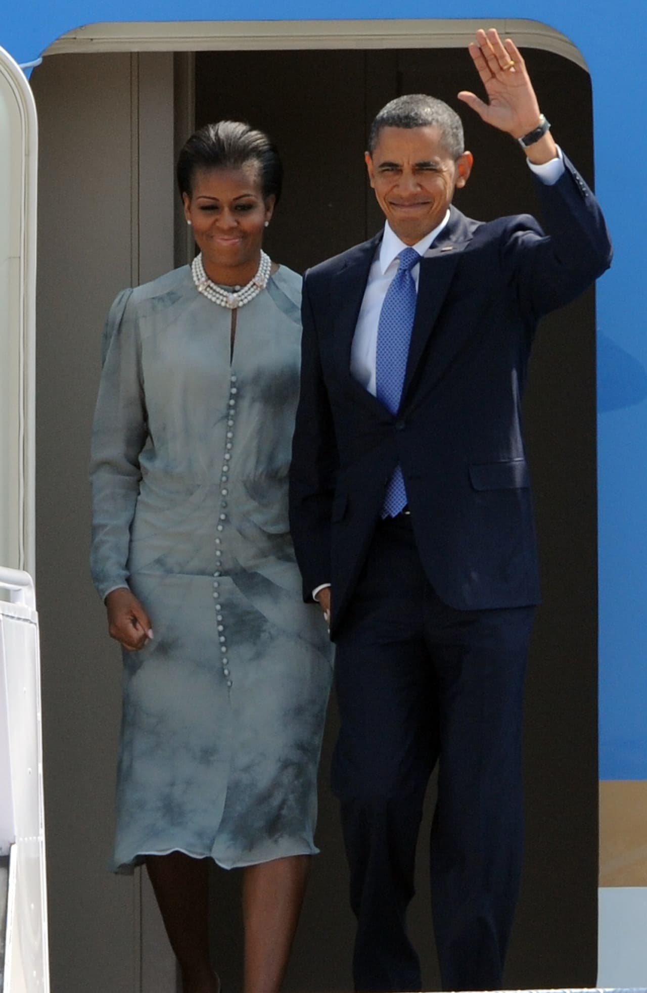 A su llegada a la India en 2010 Michelle bajó del Air Force One con un vestido de seda gris con sombreados, botonadura central y cuello caja sobre el que se puso un gran collar de perlas.