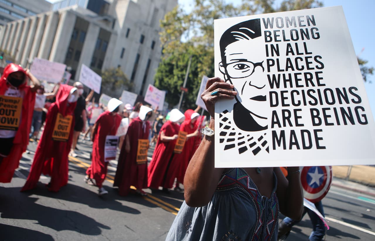 Una manifestante en Los Ángeles protesta portando una cartelera con una de las frases célebres de la jueza Bader Ginsburg: "Las mujeres pertenecen a todos los lugares donde se toman decisiones".