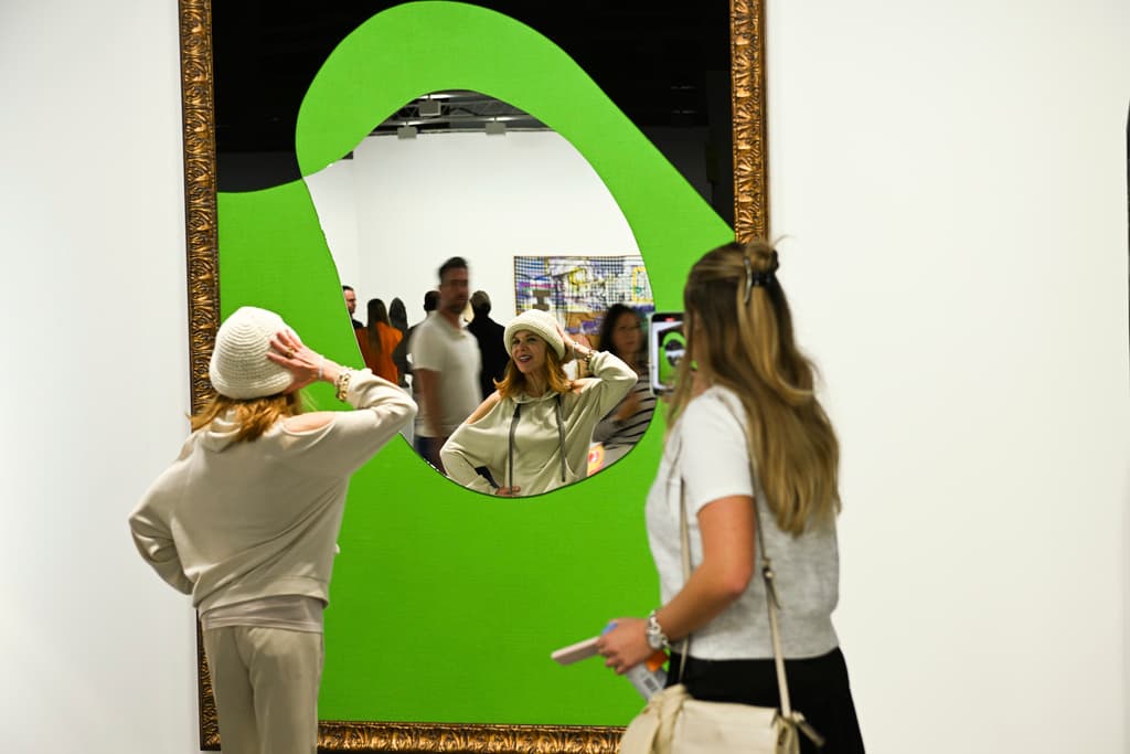 Algunos espectadores se divierten al reflejarse en una obra que se exhibe en la feria de Art Basel