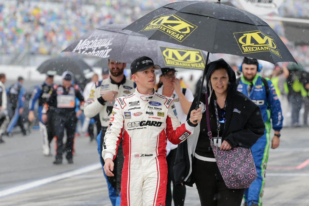 John Hunter Nemechek, a la izquierda, camina por la pista de Daytona mientras llueve. Es la segunda vez en 62 años que la llamada "Gran Carrera de Estados Unidos" debe culminarse un lunes. El primer retraso en la carrera se dio poco después de que la caravana de Trump completó su recorrido de dos millas y media por la pista. En ese momento comenzó el primer chubasco que obligó a los competidores a frenarse temporalmente en sus paradas.