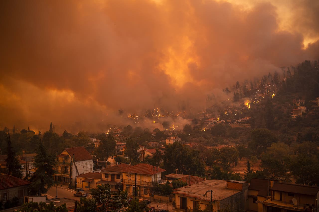 Evia es una isla escarpada con bosques y ensenadas. El humo y la ceniza de los fuegos bloquearon el sol y el cielo se volvió naranja. En la fotografía, llamas arrasan el pueblo de Gouves.
