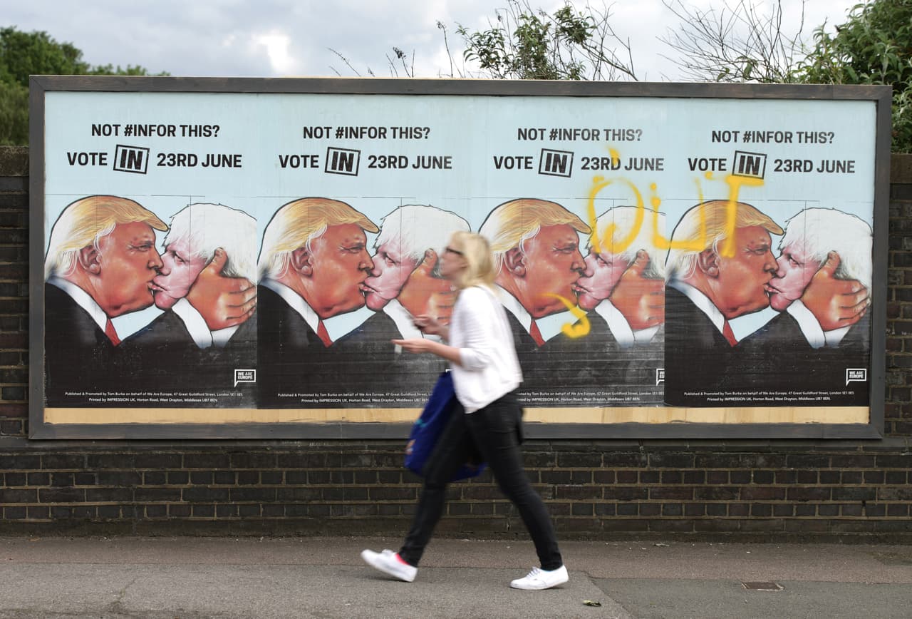 Una mujer camina frente a carteles a favor de votar por la permanencia de Gran Bretaña en la Unión Europea, en Londres, 21 de juniio de 2016. En el cartel aparece el candidato republicano estadounidense Donald Trump besando al principal partidario de la salida británica, Boris Johnson. (Yui Mok / PA via AP) UNITED KINGDOM OUT - NO SALES - NO ARCHIVES