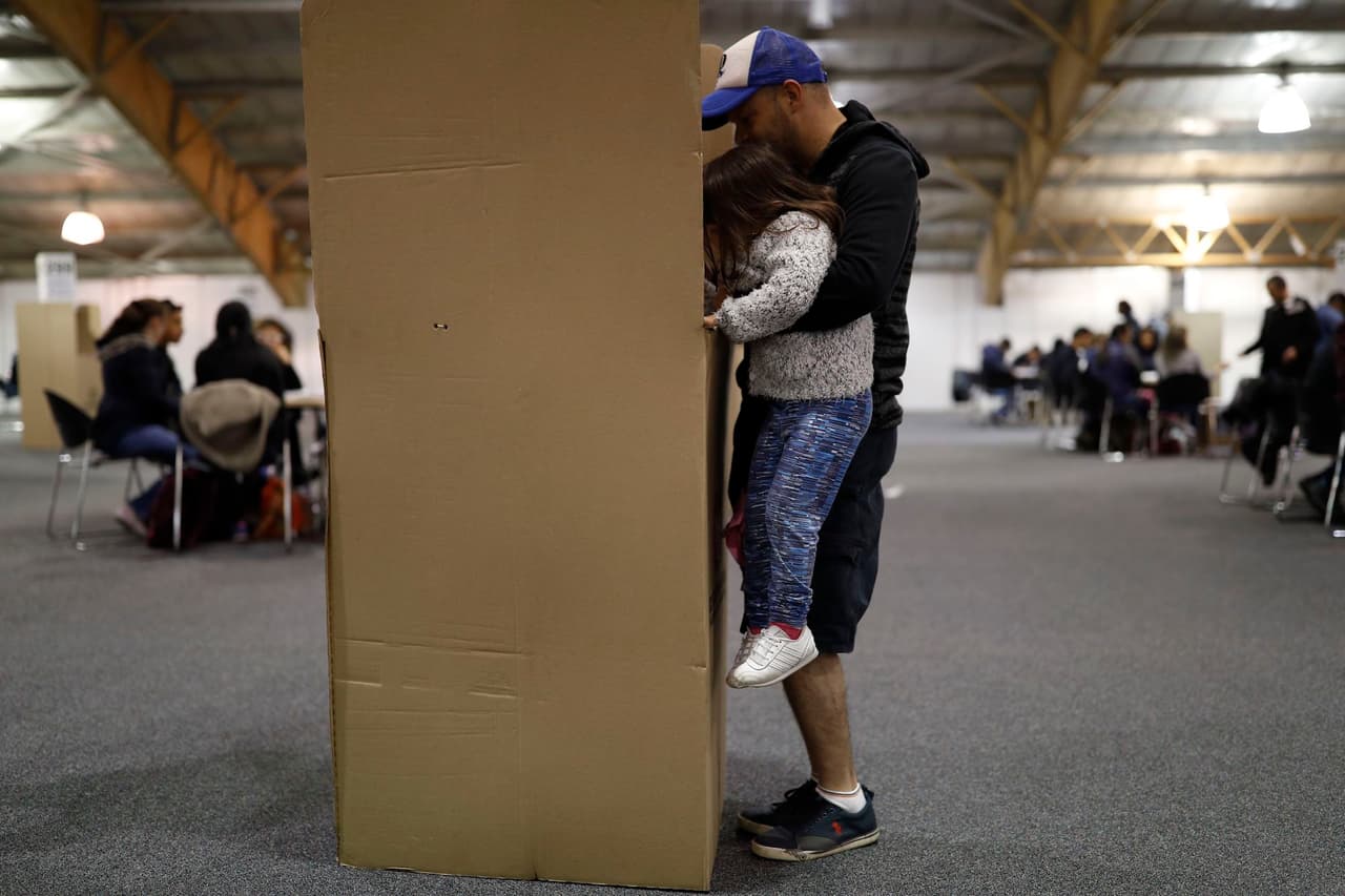 Este hombre deja que su hija marque la boleta de votación.
