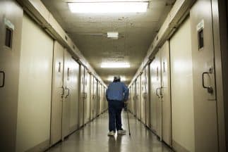 La imagen muestra a un preso caminando por un pasillo de una prisión en California.