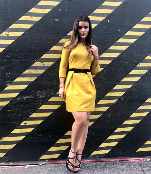 Aquí la vemos con un vestido casual corto en amarillo, con un delgado cinturón negro que remarca su cintura.