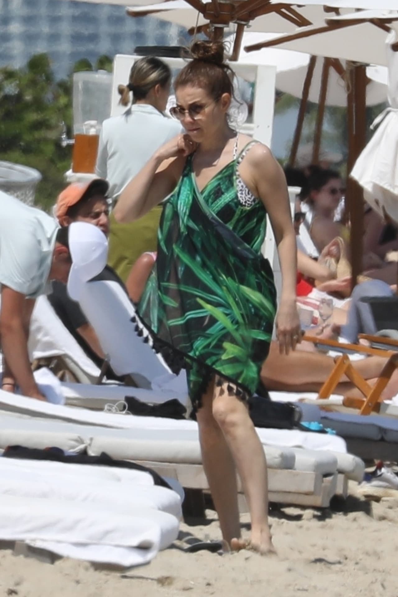 Se subió un poco el pantalón y se puso esta bata cruzada y estampada con hojas verde esmeralda con fondo negro.