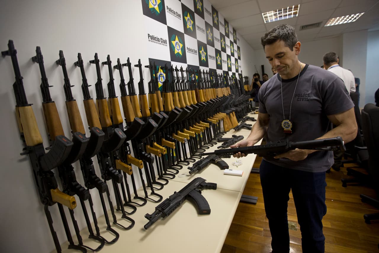 A police officer holds a confiscated automatic rifle during a press conference in Rio de Janeiro, Brazil, Thursday, June 1, 2017. Brazilian police say they confiscated 60 automatic rifles found in a cargo shipment at Rio de Janeiro's international airport. The weapons were found Thursday in a container with pool heaters in a shipment from Miami, and four people have been arrested. (AP Photo/Silvia Izquierdo)