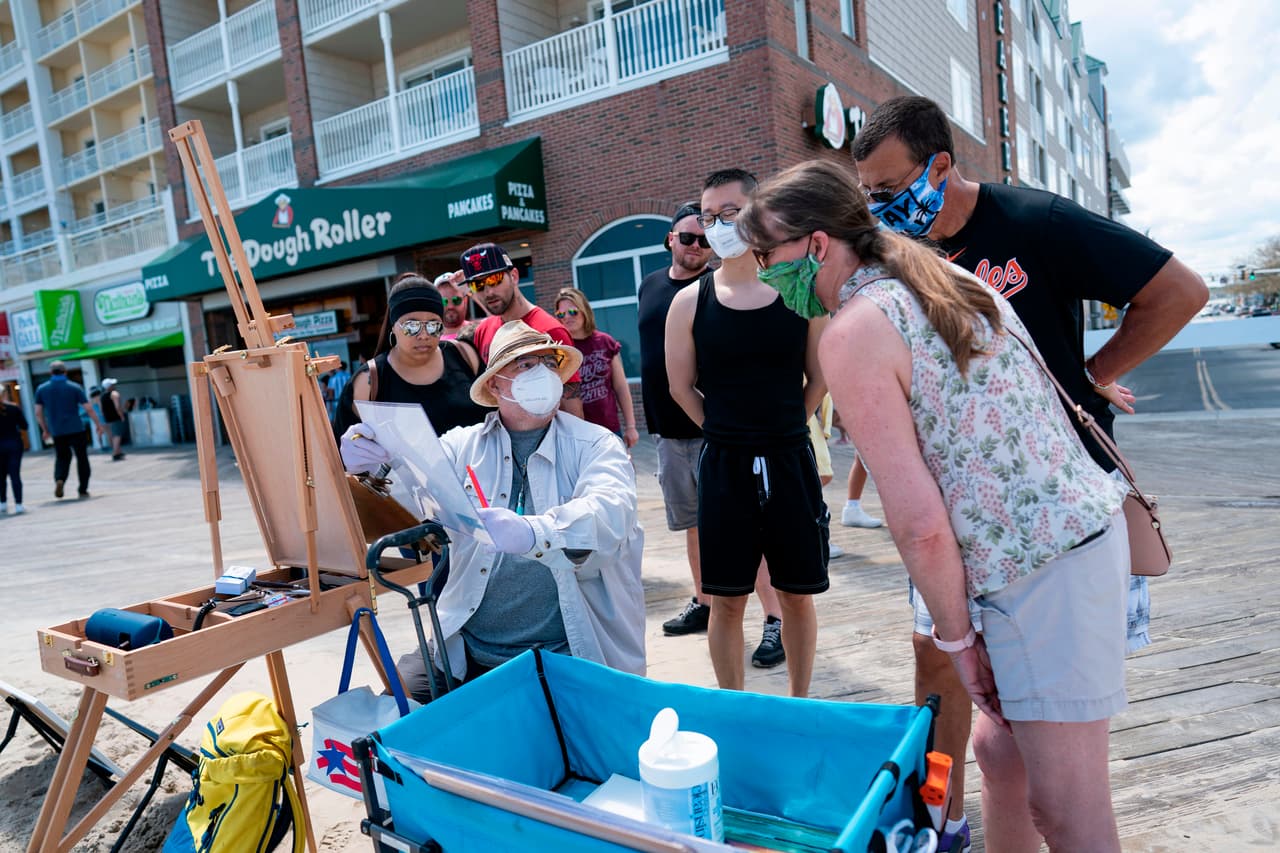 Un artista local entretiene a un grupo de los visitantes del paseo marítimo de Ocean City, Maryland, el 23 de mayo. Desde principios de este mes en este estado están permitidos los paseos por la playa, que se mantienen concurridas.
<br>