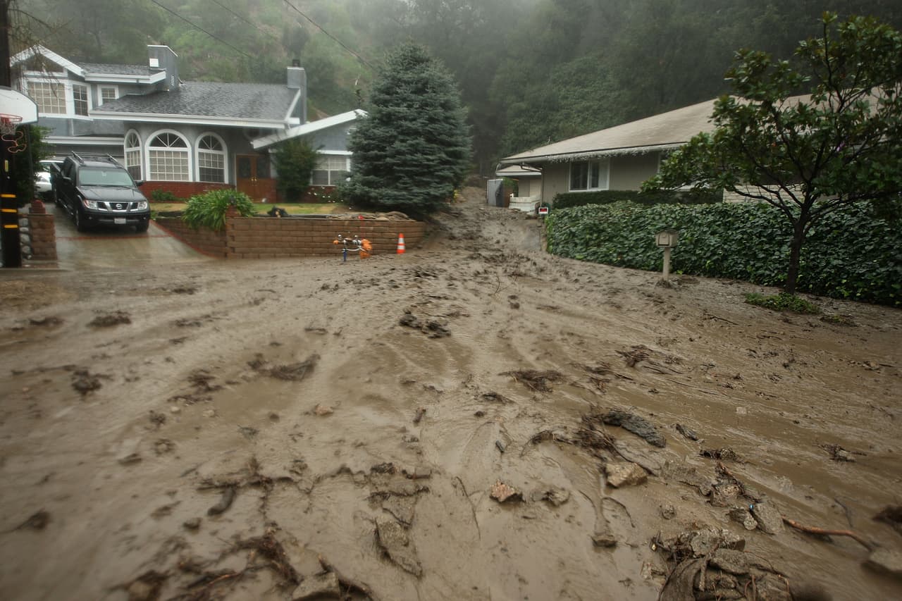 LA CANADA FLINTRIDGE, CA - JANUARY 21: Mud flows between houses and into the street in an evacuated neighborhood during the fourth storm of the week on January 21, 2010 in La Canada Flintridge, California. Hundreds of homes have been evacuated because of the threat of major mud slides and debris flows below foothills and mountains that burned last year. Despite warnings by firefighters that they will not be able to get through debris flows to rescue stay-behind residents if a major event occurs, many refuse to leave. The threat is particularly high near the San Gabriel Mountains which were denuded of natural flood-controlling vegetation by the 250-plus square mile Station Fire. (Photo by David McNew/Getty Images)