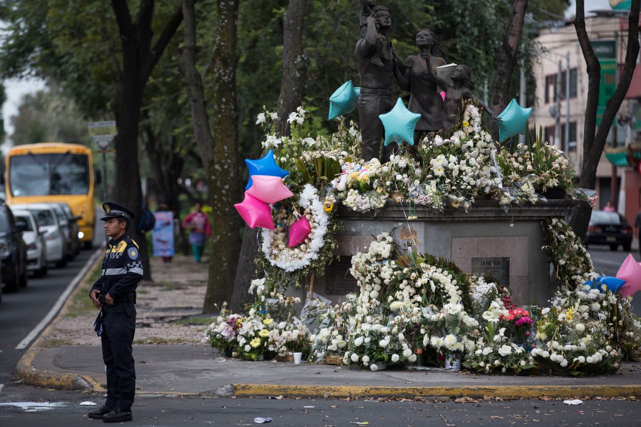 En memoria de las víctimas del Colegio Enrique Rébsamen, donde fallecieron 19 niños y 7 adultos, la gente colocó flores blancas y coronas en torno a una estatua que representa a una familia.
