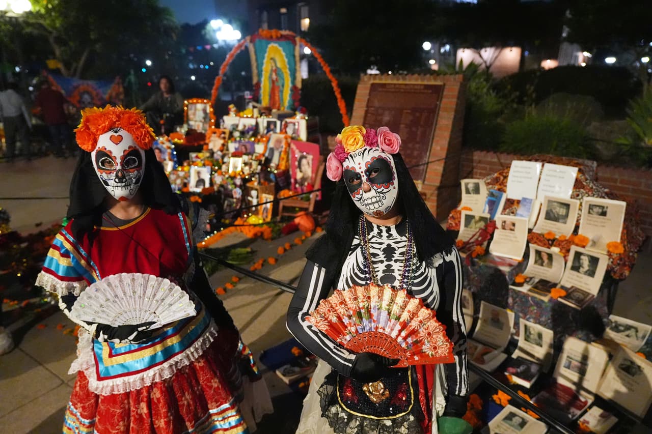 Gente junto a puestos de la calle Olvera en una procesión nocturna durante el Día de Muertos, el domingo 26 de octubre de 2025, en Los Ángeles.