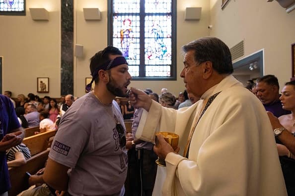 Uno de los hombres que llleva sobre sus hombros las imágenes comulga en la misa.