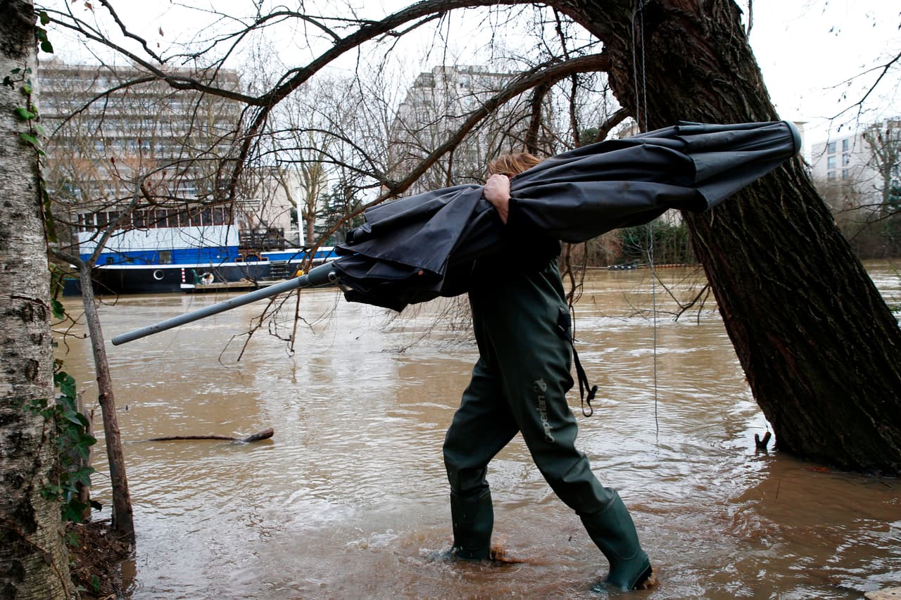 Un hombre camina con el agua hasta los tobillos por una calle cercana al río Sena, en el oeste de París. A los turistas y lugareños se les aconsejó alejarse de las orillas por temor a que puedan quedar atrapados en remolinos de agua