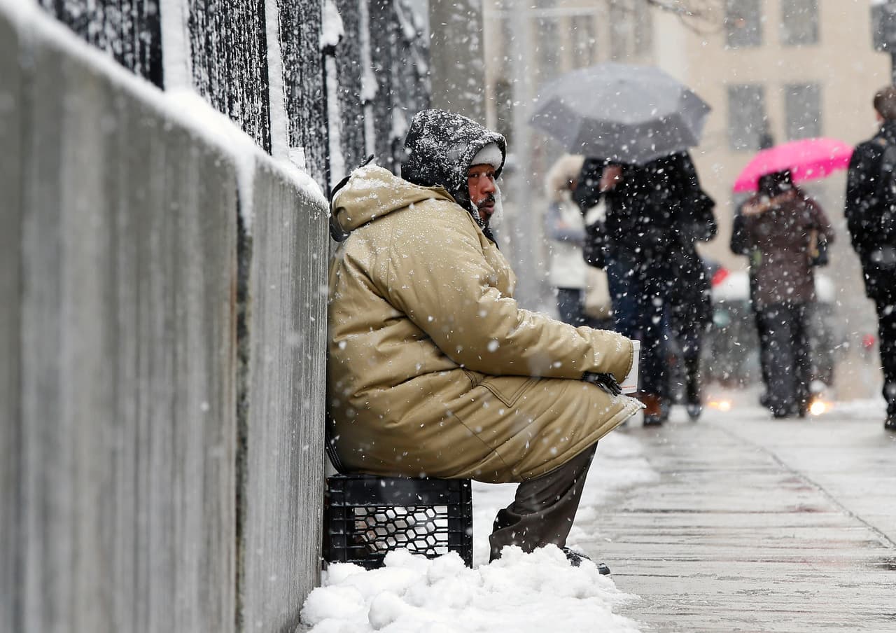 George "Big G" Dagracia solicita dinero a los transeúntes bajo la nieve ligera en Boston.