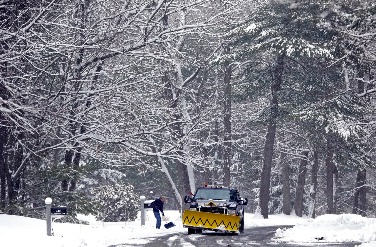 Un camión quitanieves pasa por un camino lleno de nieve en North Andover, Massachusetts.