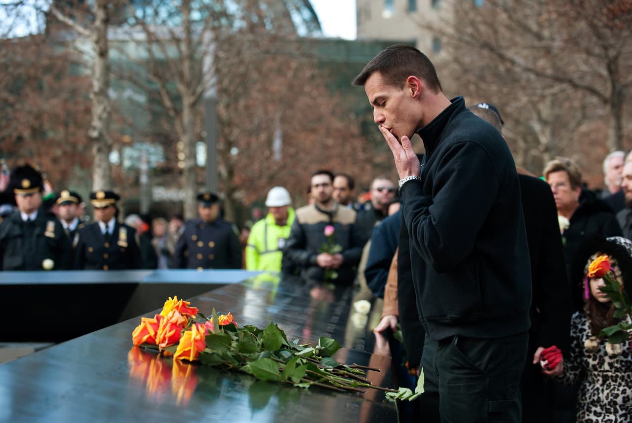 Un familiar de una víctima de los atentados contra el World Trade Center deja una rosa en el memorial que se colocó en el lugar. (Foto por Bryan Thomas).