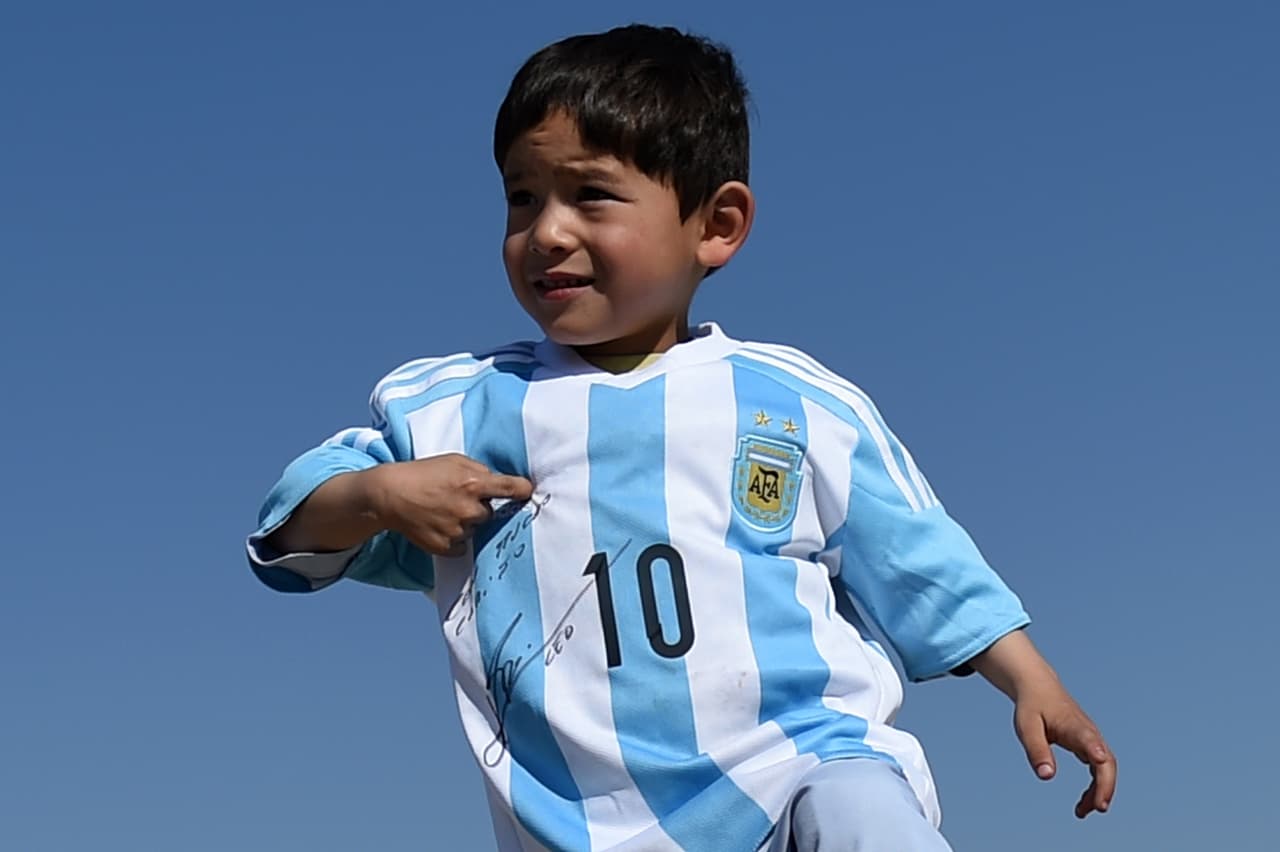 Murtaza Ahmadi, el pequeño afgano fan de Lionel Messi, posa en Kabul la camisa autografiada que le envió el astro argentino. (Foto por Wakil Kohsar, AFP).