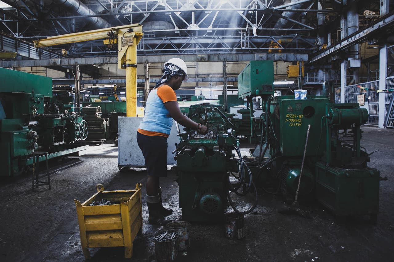 Una trabajadora, tornera, en plena faena. Moa, lugar poco conocido para los medios alberga algunas preguntas. ¿Son seguras las practicas mineras en Moa? ¿Cómo se recuperara el visible daño causado al ambiente? ¿Qué se hace para evitarlo? ¿Por qué la planta Che Guevara, de gestión estatal, está casi en la ruina? ¿Hasta dónde tendrán que llegar las consecuencias para la salud de sus pobladores? ¿Los habitantes de tan rico pueblo, dónde ven su riqueza?