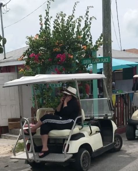 Lili haciendo de paparazzi fotografía a su relajada tía Gloria Estefan mientras hablaba por teléfono a la sombra de este carro de golf en agosto del 2017.