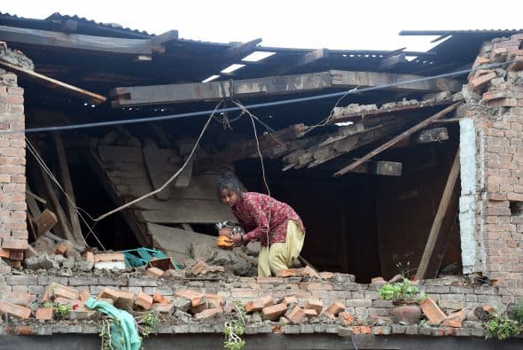 Una niña nepalí rescata pertenencias de entre los escombros de su casa.