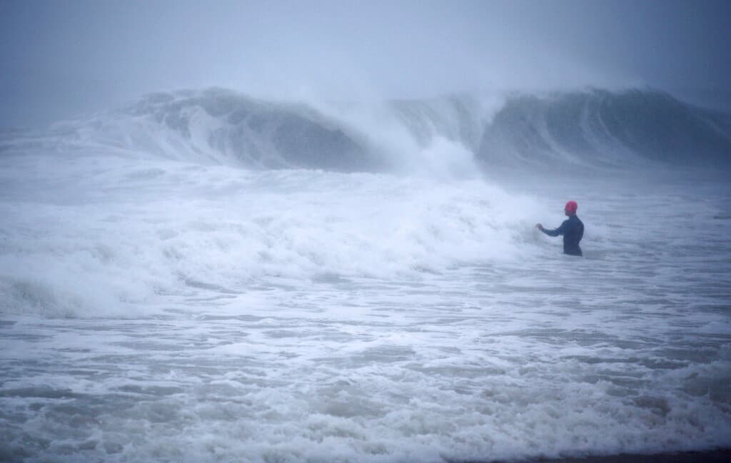 En la imagen: Matt Prue, de Stonington, Connecticut, entra al mar para surfear las olas ocasionadas por Henri, cuando se acercaba a tierra este domingo.