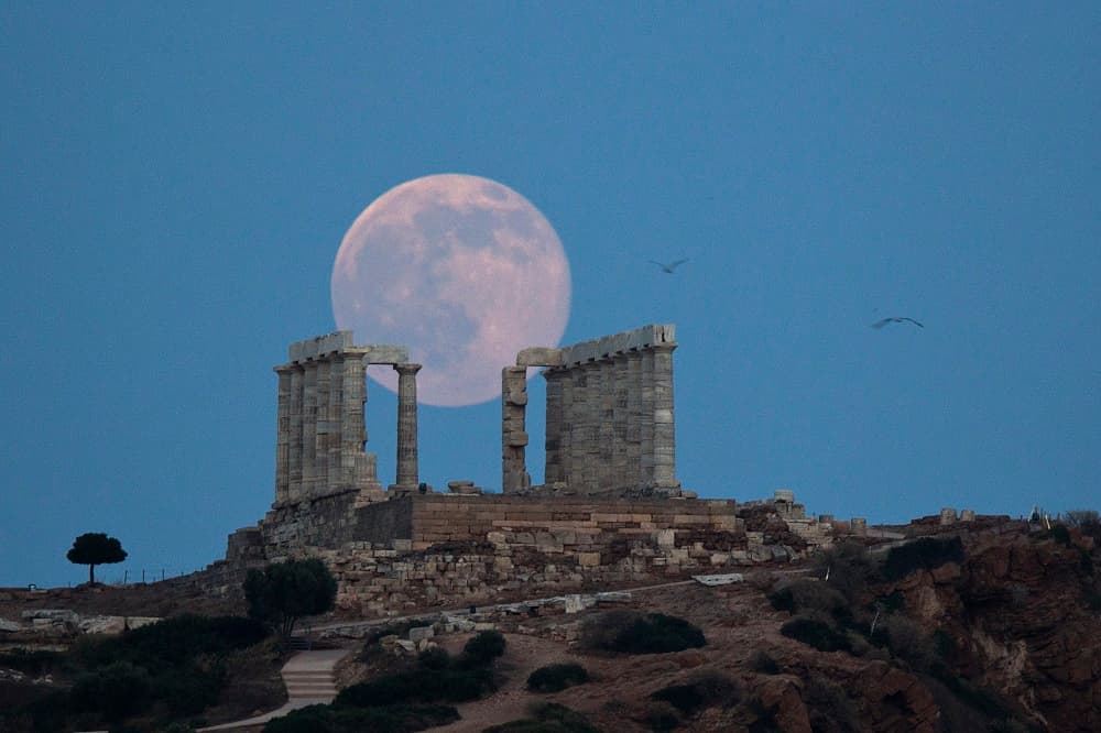 La "luna de fresa" se recorta sobre las ruinas del templo de Poseidón, en el sureste de Atenas. Poseidón era el dios del mar.