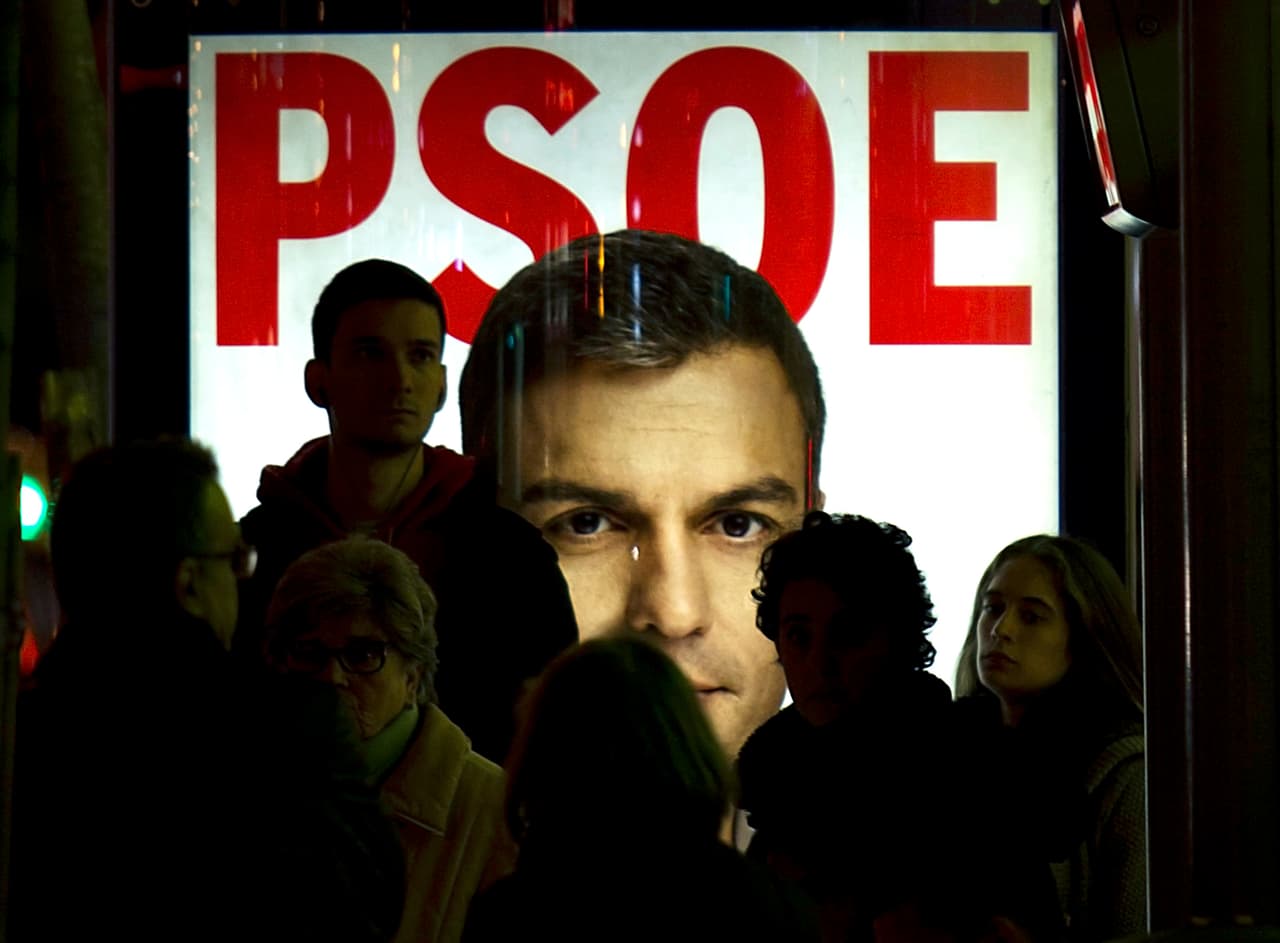 Varias personas delante de un cartel de Pedro Sánchez.