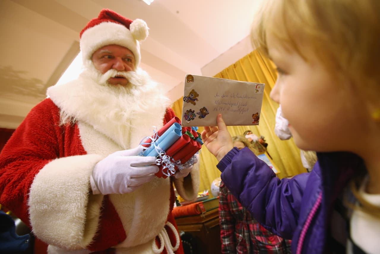 HIMMELPFORT, GERMANY - NOVEMBER 18: Mia, 4, who was visiting with her class of daycare children, hands her letter of Christmas wishes to Santa Claus, in German called der Weihnachtsmann, at the post office on November 18, 2014 in Himmelpfort, Germany. Every Christmas season German state postal carrier Deutsche Post maintains the official Santa Claus post office in Himmelpfort ("Himmelpfort" translates to "Heaven's Gate"), where on average 300,000 letters a year addressed to Santa Claus arrive from young and old all over the world. Santa and his team of 20 angels, all employed by Deutsche Post, respond to every letter with a personalized note. (Photo by Sean Gallup/Getty Images)