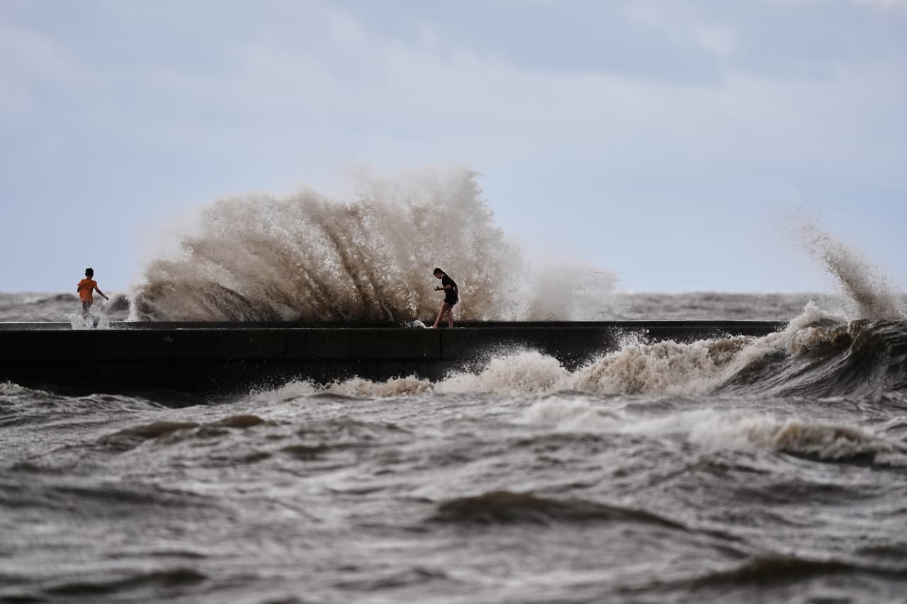 Unos niños juegan cerca de las olas que rompen en el muelle de West End, en el lago Pontchartrain, mientras la tormenta tropical Bertha se acerca a la costa de Luisiana el miércoles 22 de julio de 2026, en Nueva Orleans. (Foto AP/Gerald Herbert)
