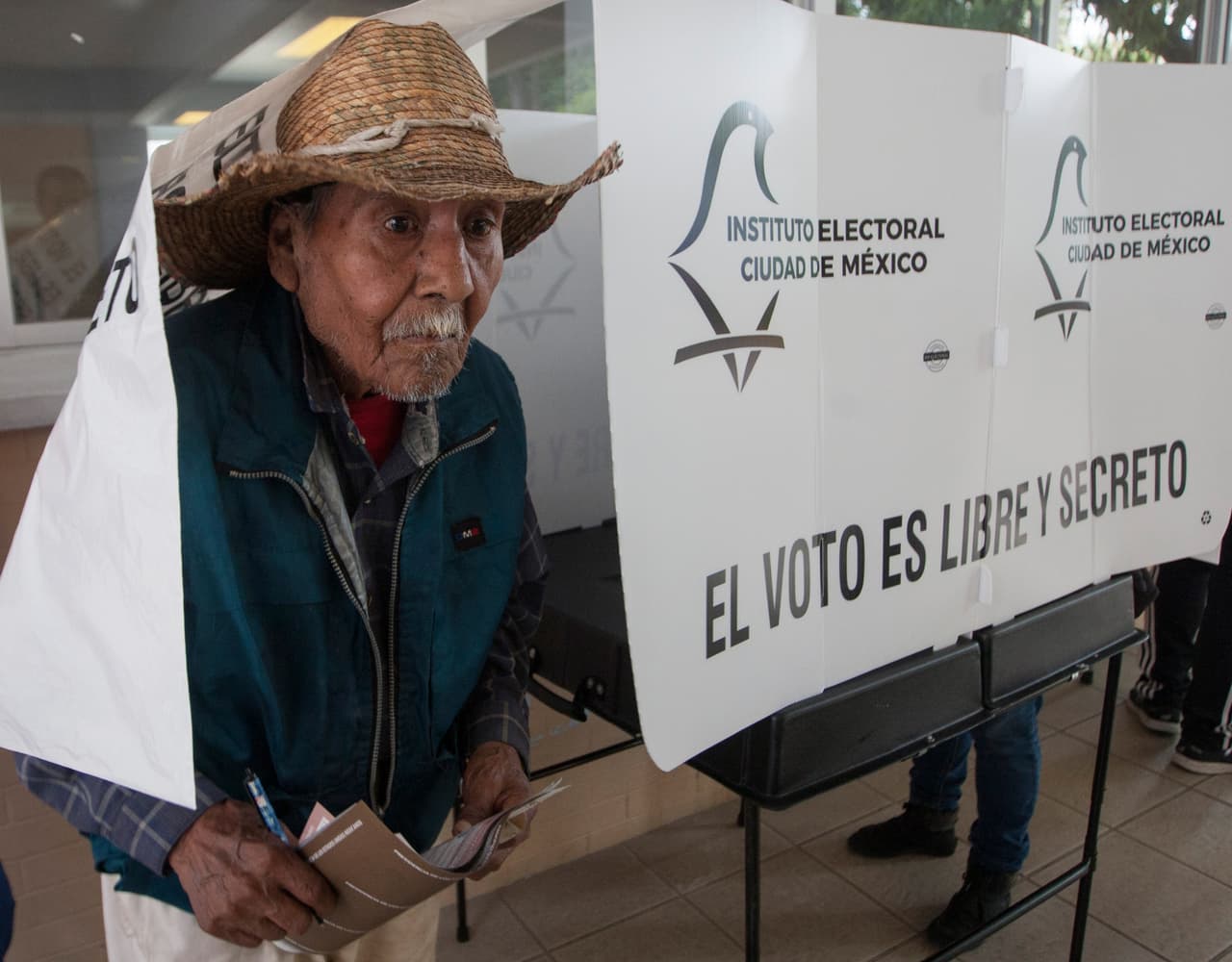 Un hombre sale de la cortina donde selecciono su voto, en una casilla de la Ciudad de México.