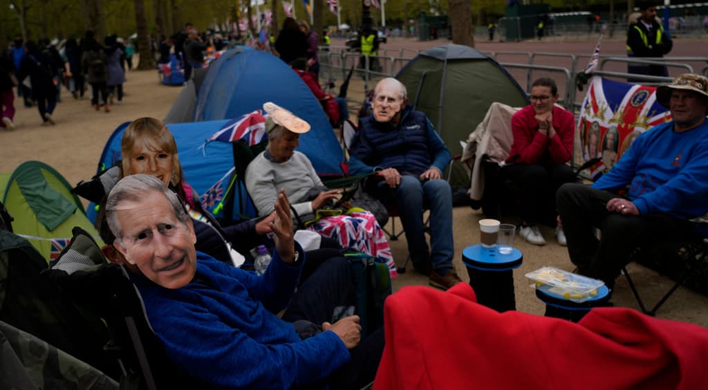 Entusiastas seguidores que acampan en el lugar llevan máscaras con la cara de miembros de la Familia Real.