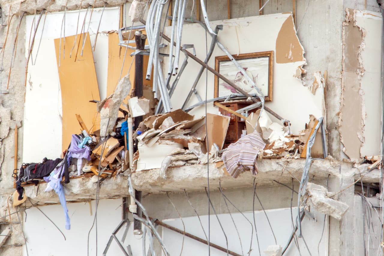 Los restos de lo que parece ser un cuarto de baño: gabinetes, ropa, productos de aseo personal y un inodoro bajo los escombros. 
<br>
<br>Personas en trajes de baño y otros interesados con sus mascotas se acercan al cerco de la policía frente al mar para ver desde lejos las ruinas. Desde allí se entiende que la estructura no estaba tan cerca del mar como parece, y a simple vista es muy difícil detallar lo que quedó en los departamentos que aún están en pie.
<br>