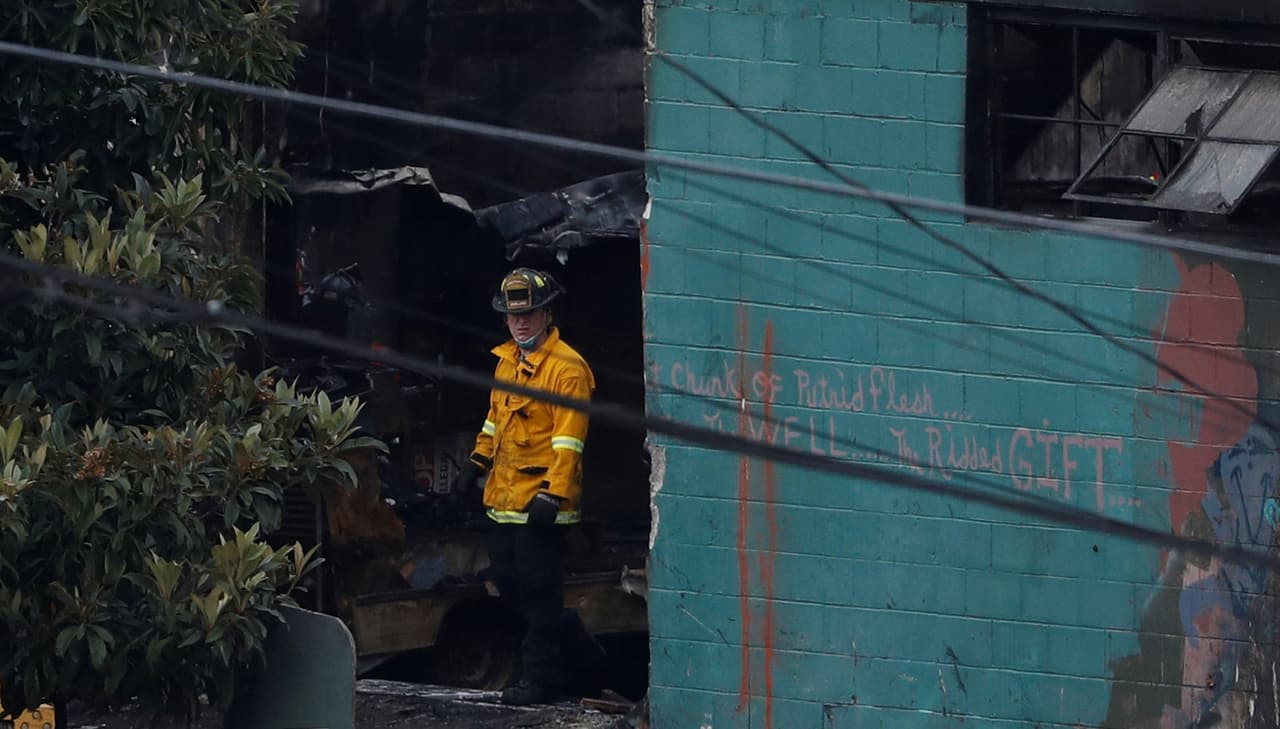 Un bombero sale del interior del almacén arrasado por las llamas en Oakland.