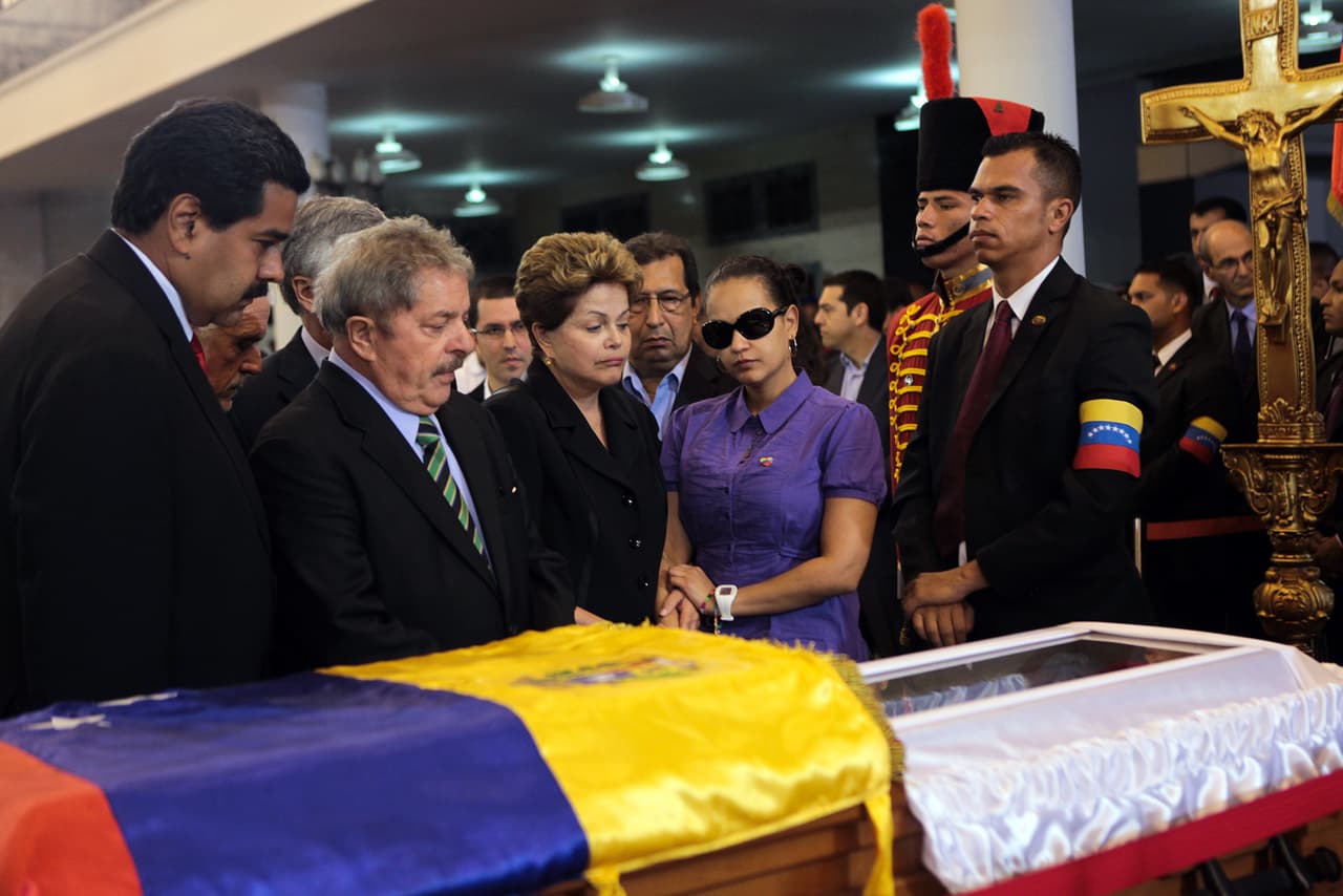 <b>La muerte.</b> El 18 de febrero, Chávez fue trasladado desde Cuba e ingresado en el Hospital Militar de Caracas. En la tarde del 5 de marzo de 2013, Nicolás Maduro anunció su muerte en cadena nacional de radio y televisión. El gobierno impuso funerales de Estado por 10 días y cientos de seguidores hicieron fila para ver su féretro expuesto en la Academia Militar de Venezuela. En la foto, junto a la urna que contenía sus restos, los expresidentes de Brasil Luiz Inacio Lula Da Silva y Dilma Rousseff; Nicolás Maduro, actual presidente de Venezuela, y Rosa Virginia Chávez, hija mayor de Hugo Chávez.