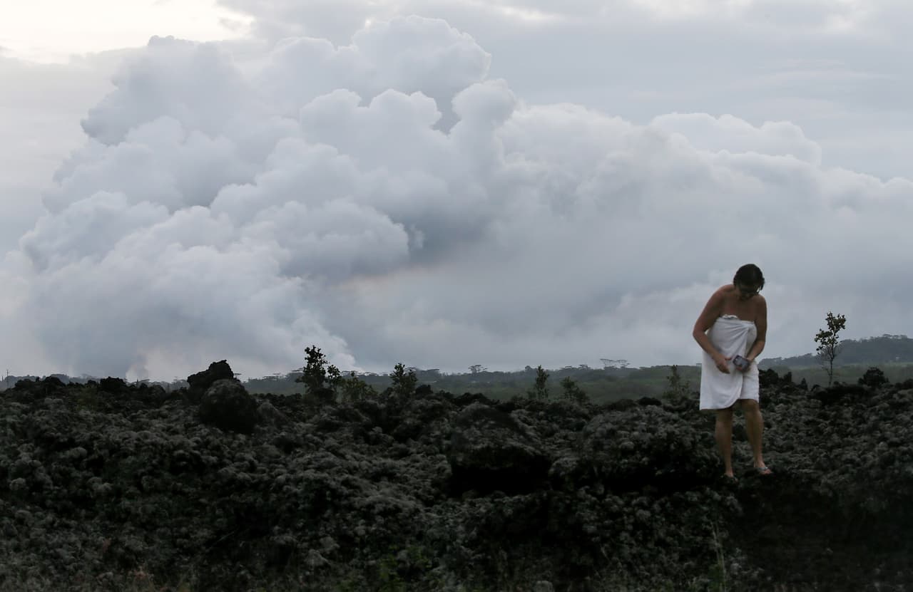Una residente, cubierta solo con una toalla de baño, salió a caminar por un antiguo flujo de lava solidificado, desde donde tomó algunas fotografías. El USGS elevó este martes a "alerta roja" el nivel de erupción del volcán y las autoridades locales recomendaron a los residentes prepararse para una evacuación muy rápida.